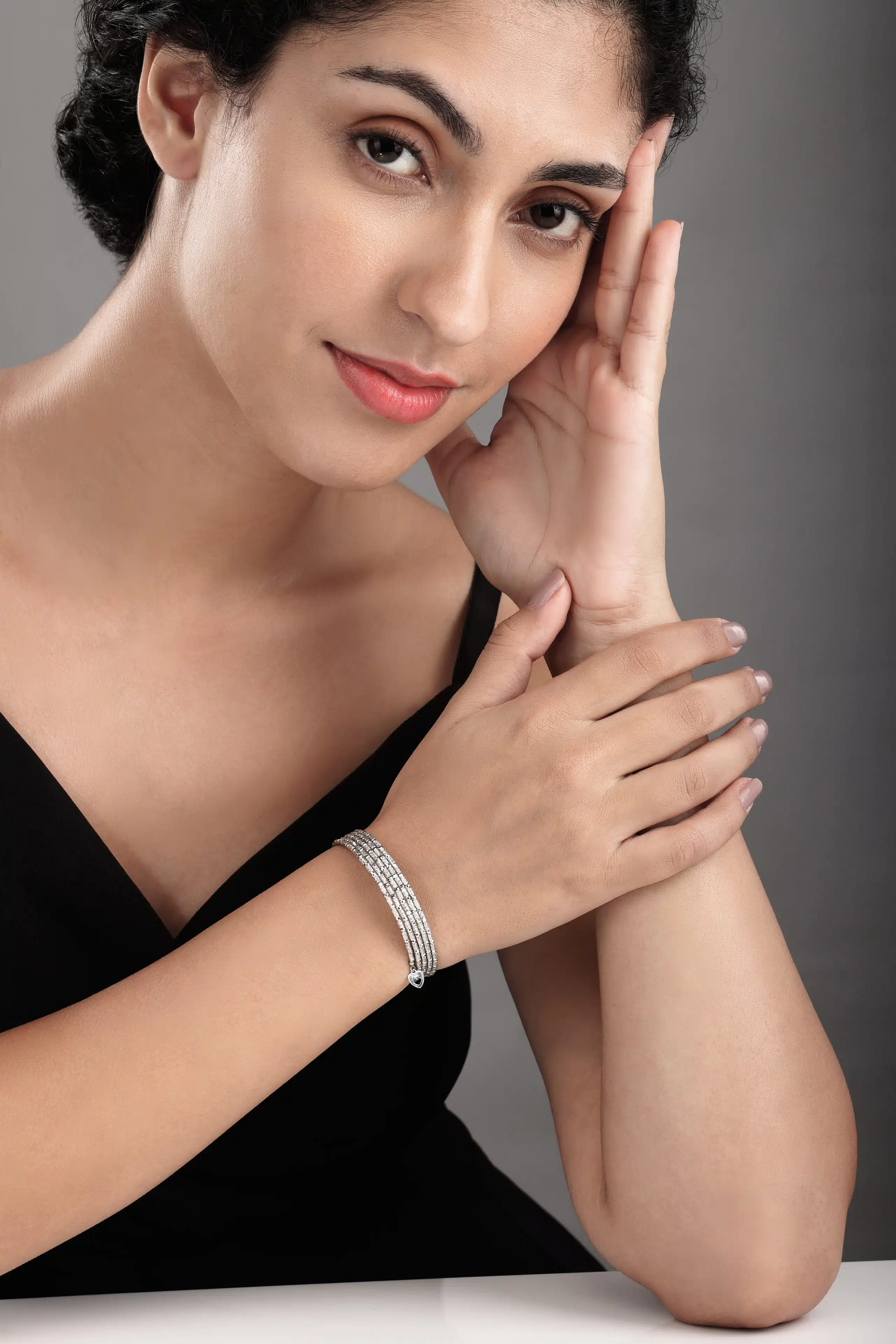 Female model in black dress posing with a platinum bracelet in her hand photographed by pankaj mathur in mumbai studio.